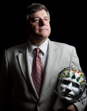 John Kounios holds a model head with an electroencephalogram (EEG) electrode cap on it.